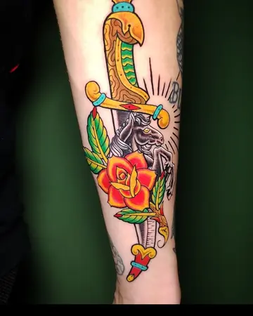 Adaga atravessando uma rosa vermelha e uma pantera, em cores, no antebraço.
